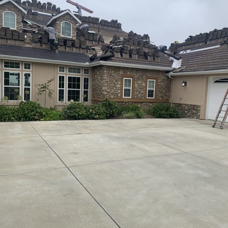 Crew installing underlayment on residential roof.